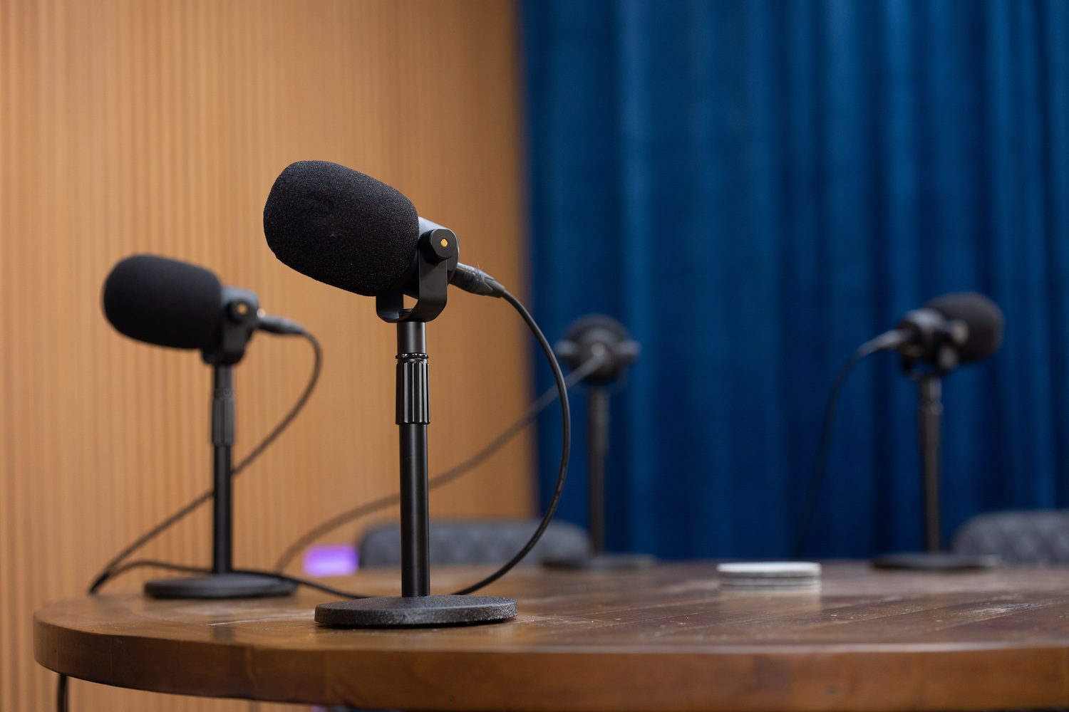 Inside a podcast studio — microphones, chairs and warm lighting set up for a session